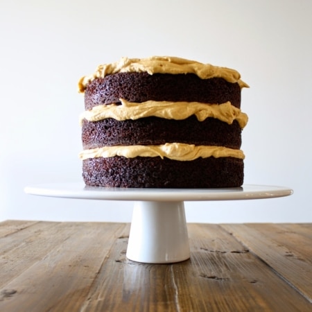A cake on a white cake stand sitting on top of a wooden table