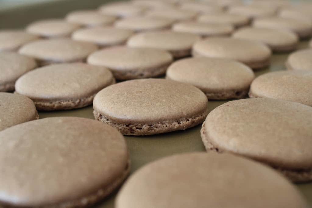 Gros plan sur les coquilles de macarons sur une plaque de cuisson