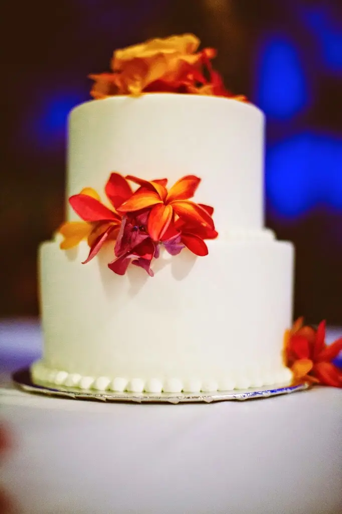 Foto einer Hochzeitstorte mit Vanille-Buttercreme und orangen Blumen.