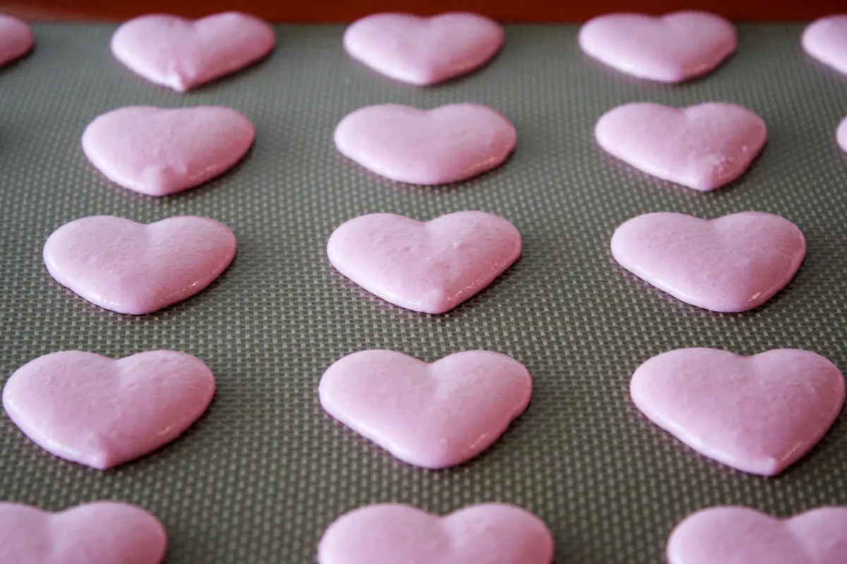 Macarons pipés sur une plaque à pâtisserie.