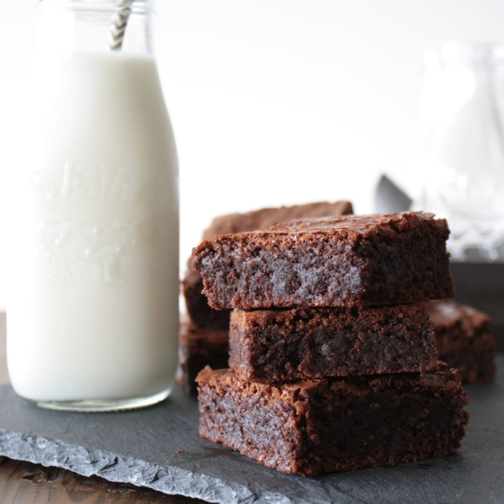 Stack of brownies with a glass of milk.