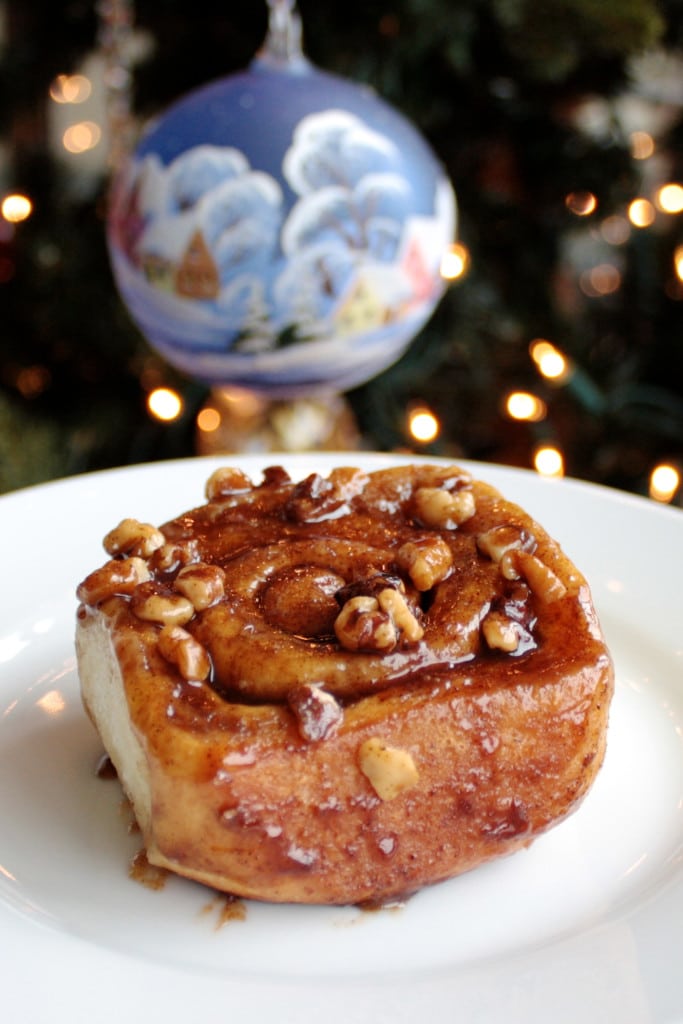 Cinnamon roll on a plate with ornament behind.