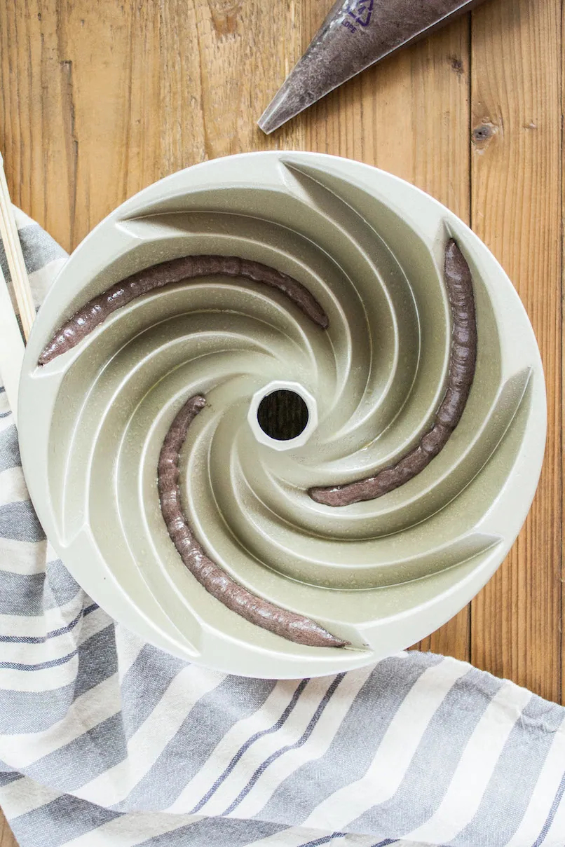 Overhead of the dark batter piped into the Bundt pan.