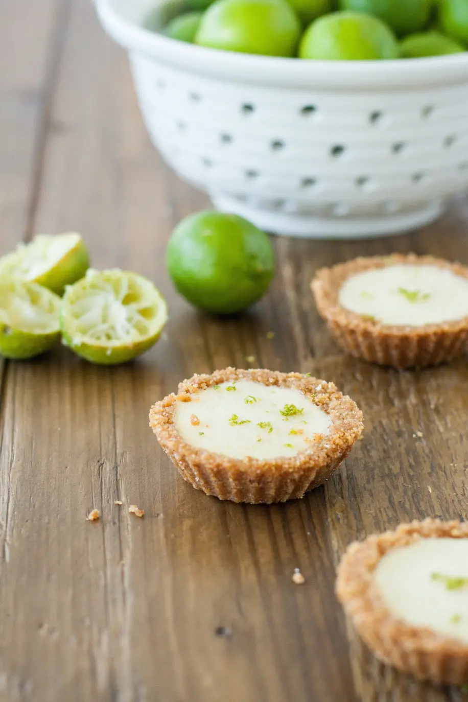 Tarts on a wooden table with limes in the background.