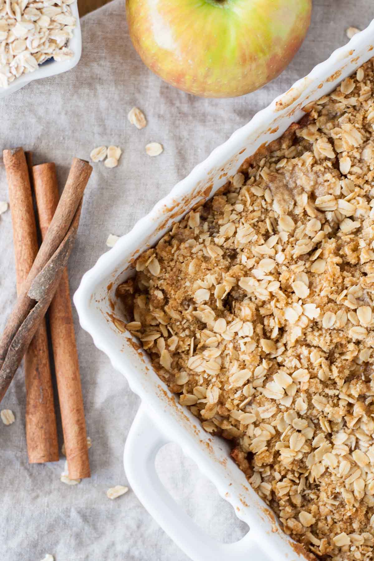 Overhead shot of apple crisp with cinnamon sticks on the side.