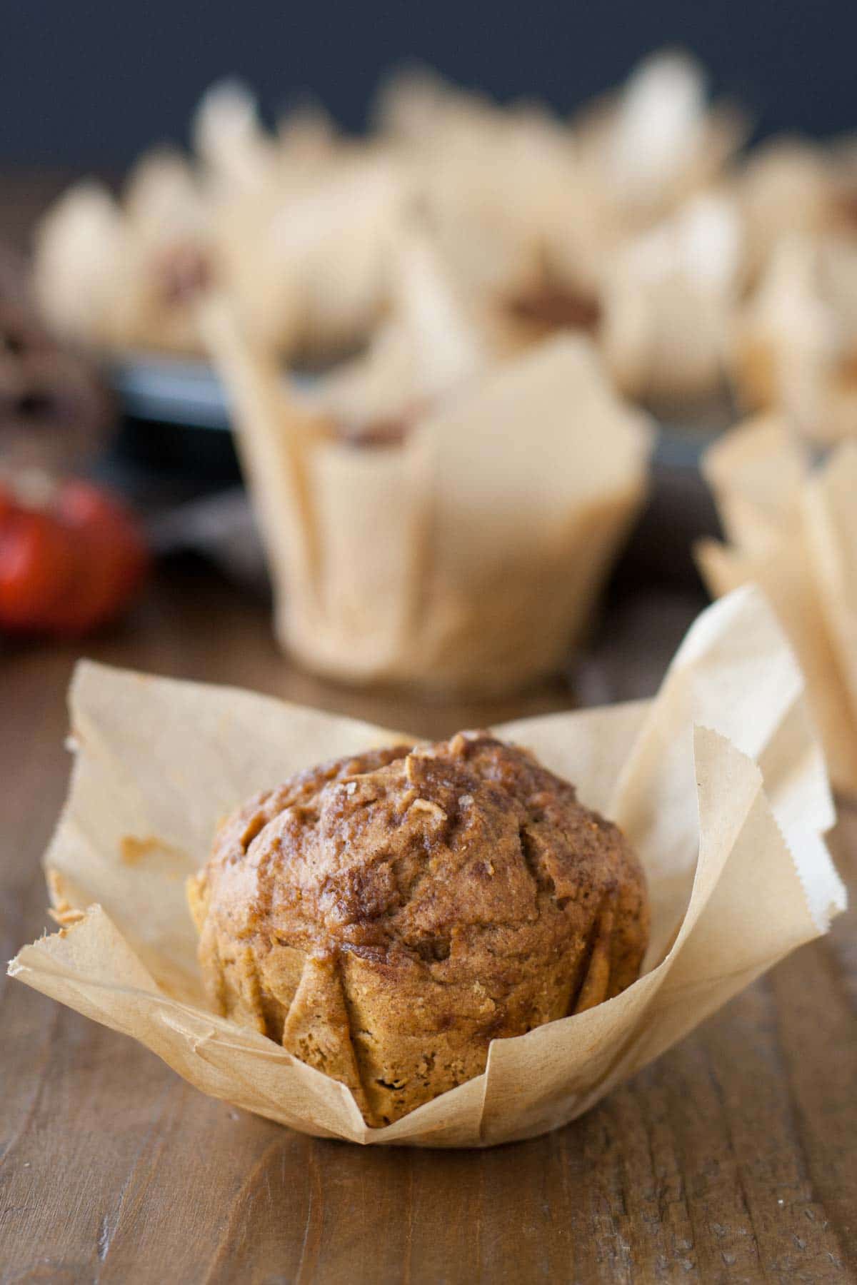 Close up of a pumpkin muffin with the parchment liner peeled back.