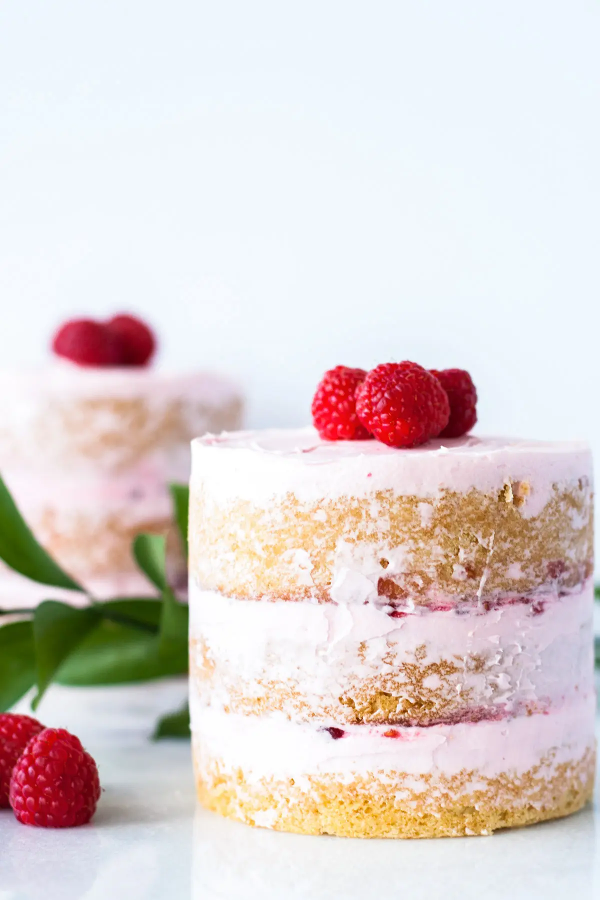 Two mini cakes decorated with fresh raspberries.