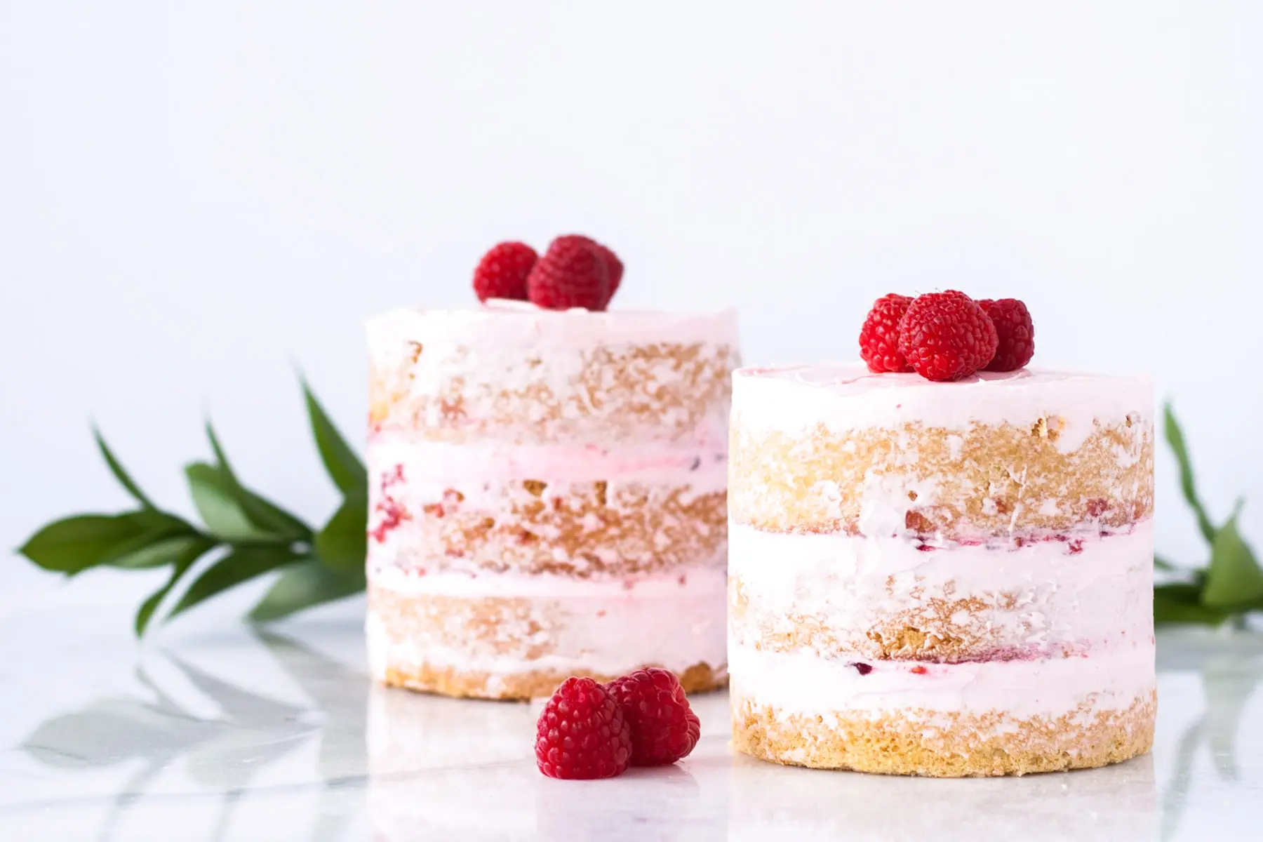 Two mini cakes decorated with fresh raspberries.