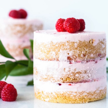 Two mini cakes decorated with fresh raspberries.
