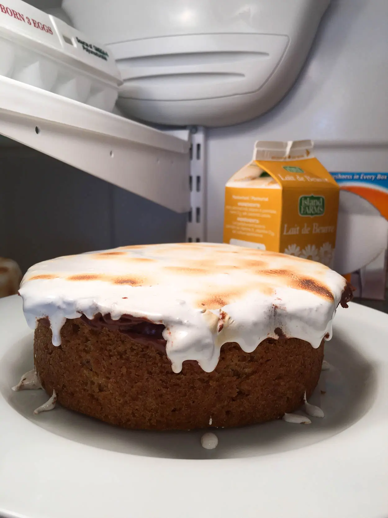 Cake layer with dripping fluff on it in the fridge.