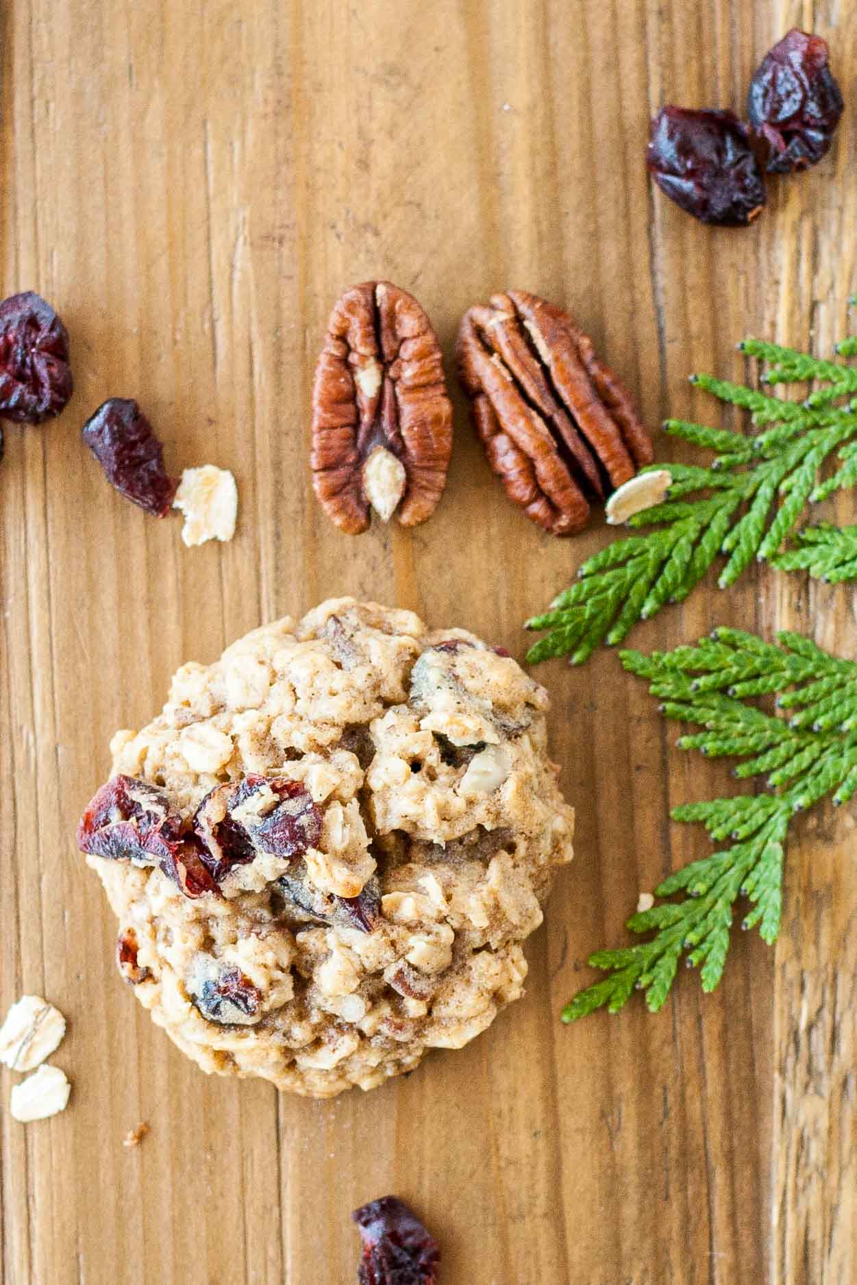 Cookie on a wooden table with pecans and dried cranberries.