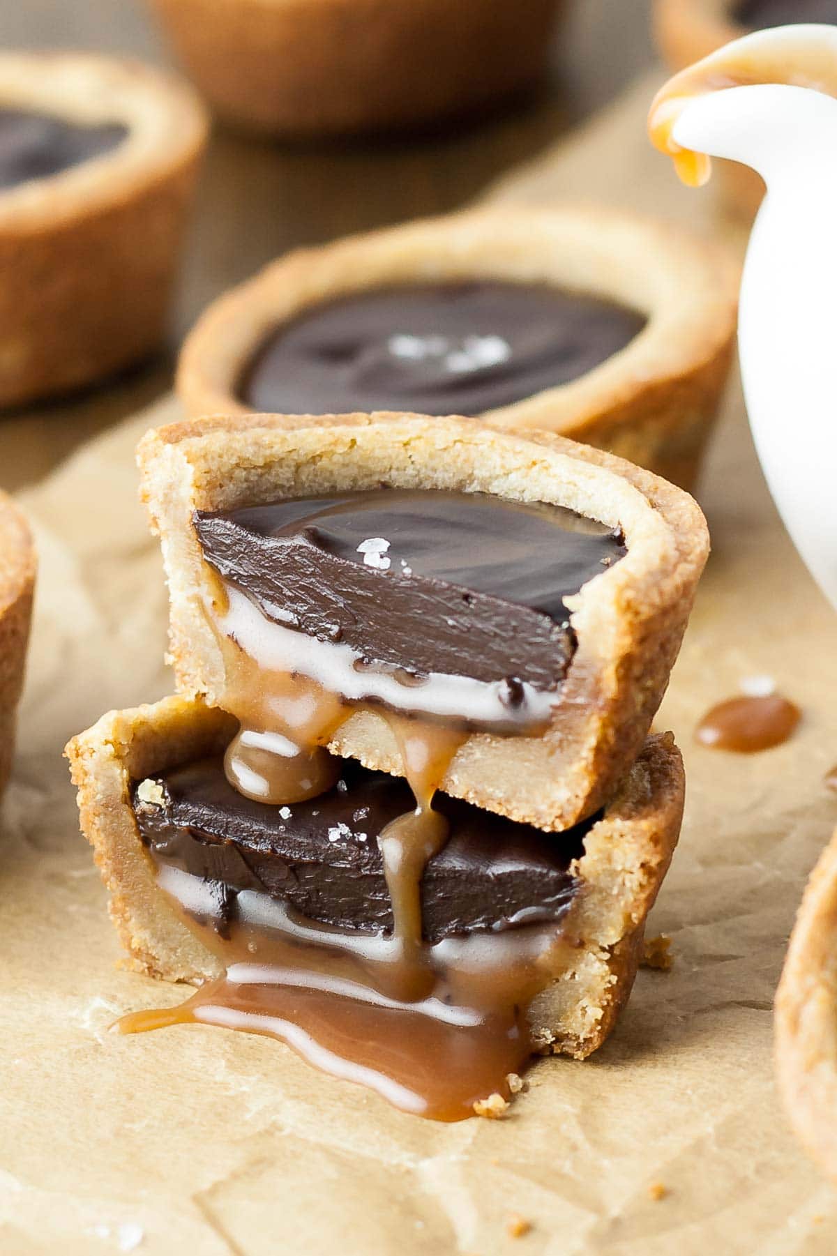 Two cookie cup halves stacked on top of each other with caramel oozing out.
