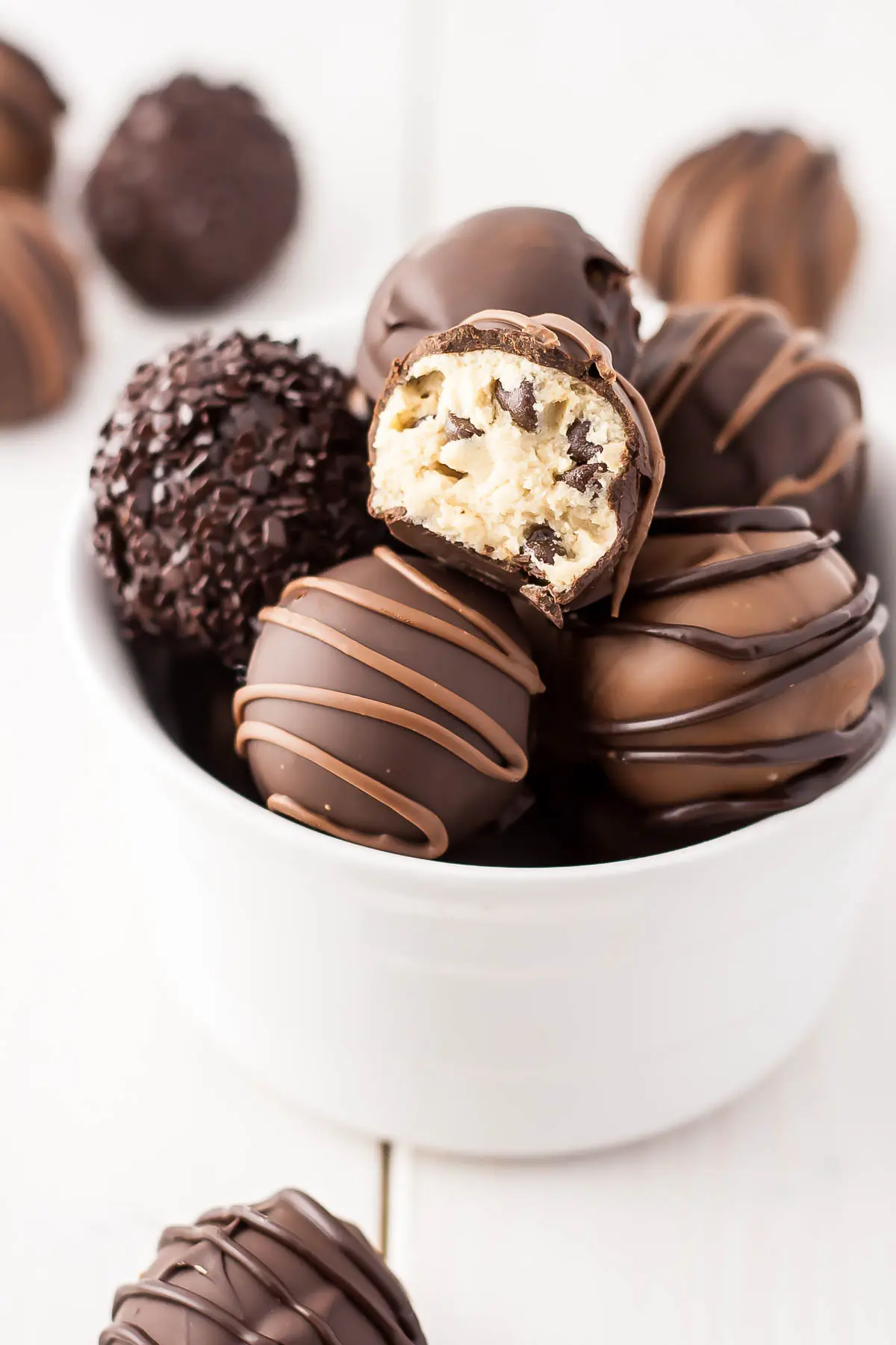 Cookie dough truffles in a bowl. One with a bite taken out.