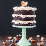 A cake sitting on top of a mint green cake stand. Creme eggs scattered all around.