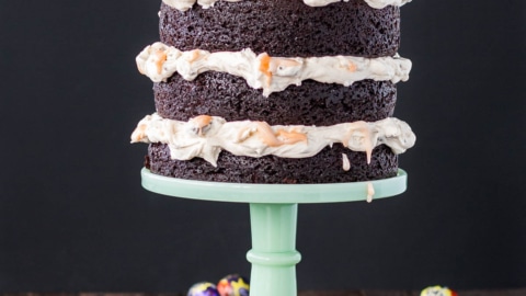 A cake sitting on top of a mint green cake stand. Creme eggs scattered all around.
