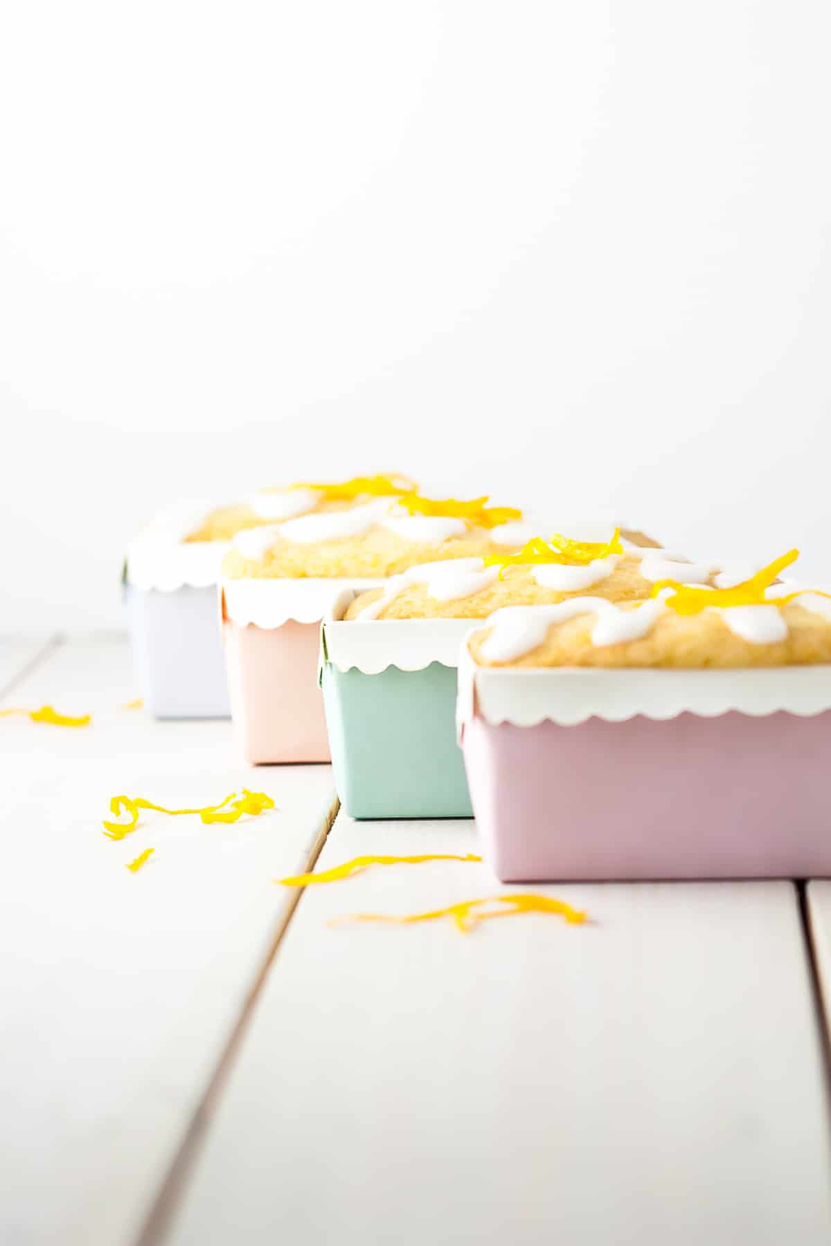 Four lemon loaves in pastel liners staggered in front of each other.