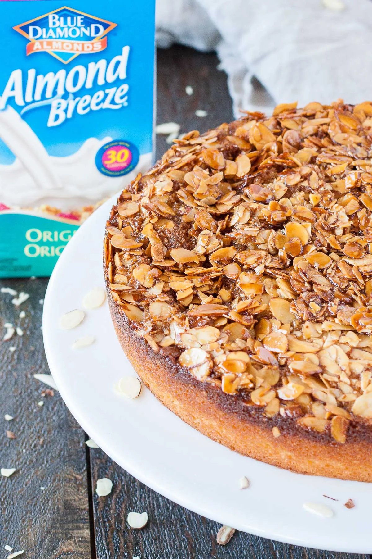 Angled shot of the almond cake with a carton of almond milk behind it.