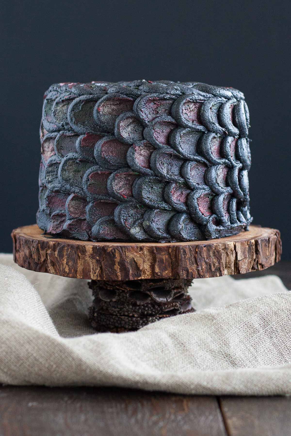 Cake decorated with dragonscales on a rustic cake stand.