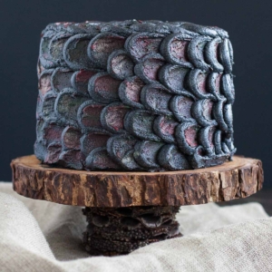 Cake decorated with dragonscales on a rustic cake stand.