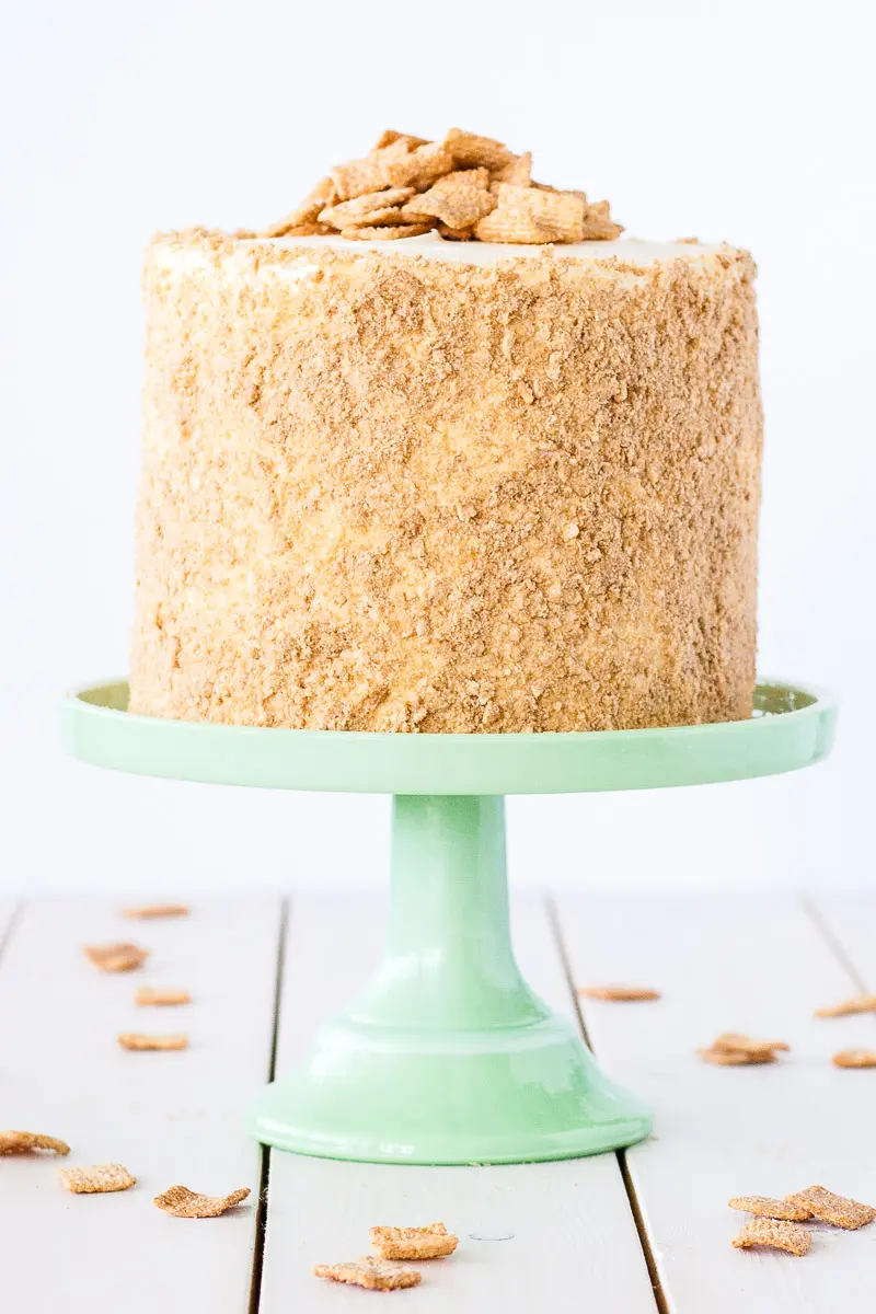 A cake sitting on a mint green cake stand and a black background.