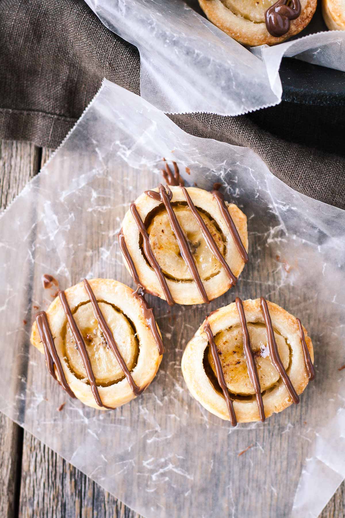 Banana bites drizzled with chocolate on a piece of parchment.
