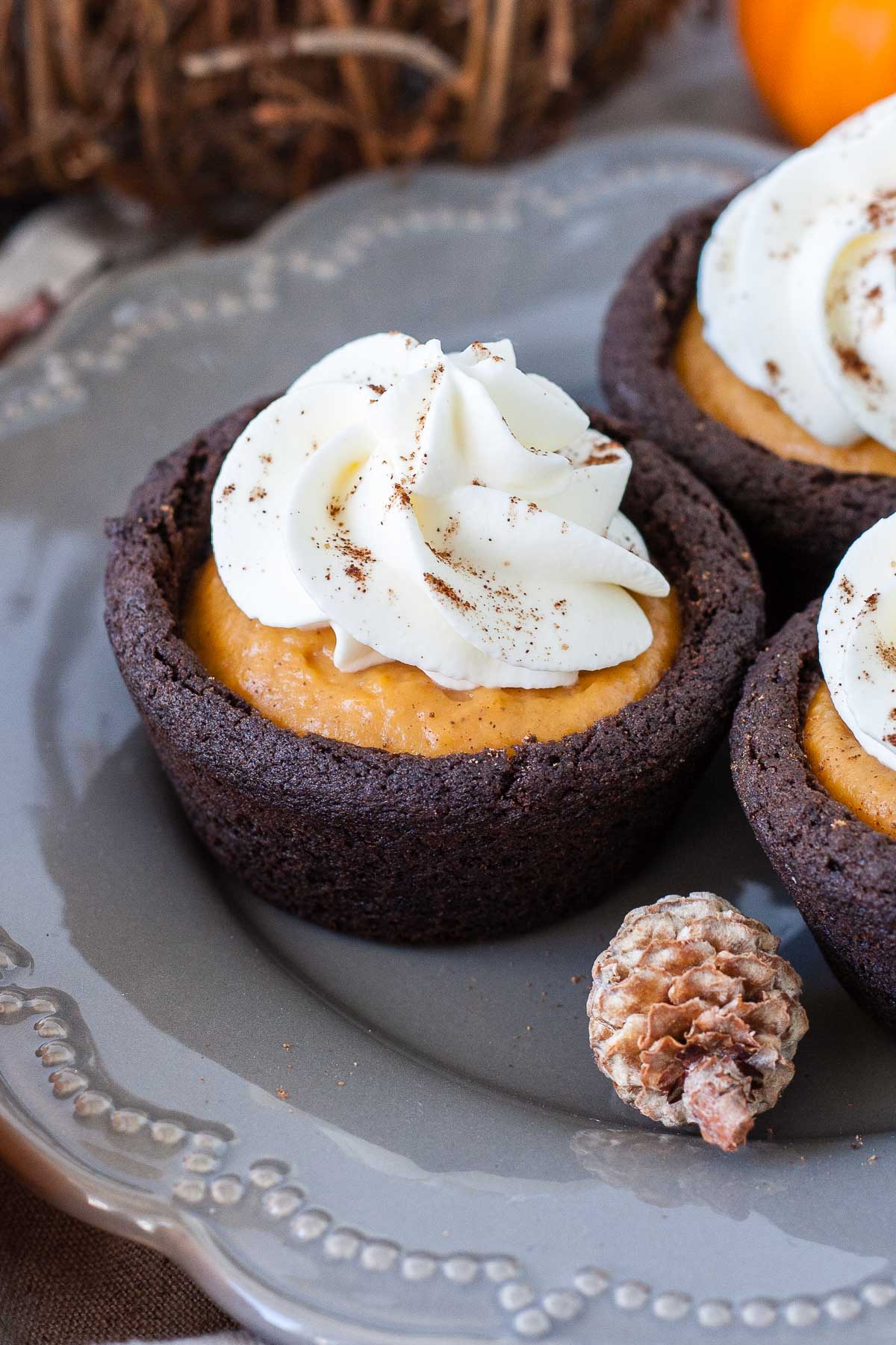 Cookie cups topped with whipped cream on a grey plate.