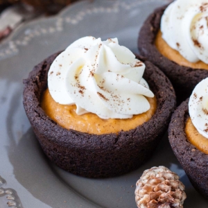 Cookie cups topped with whipped cream on a grey plate.