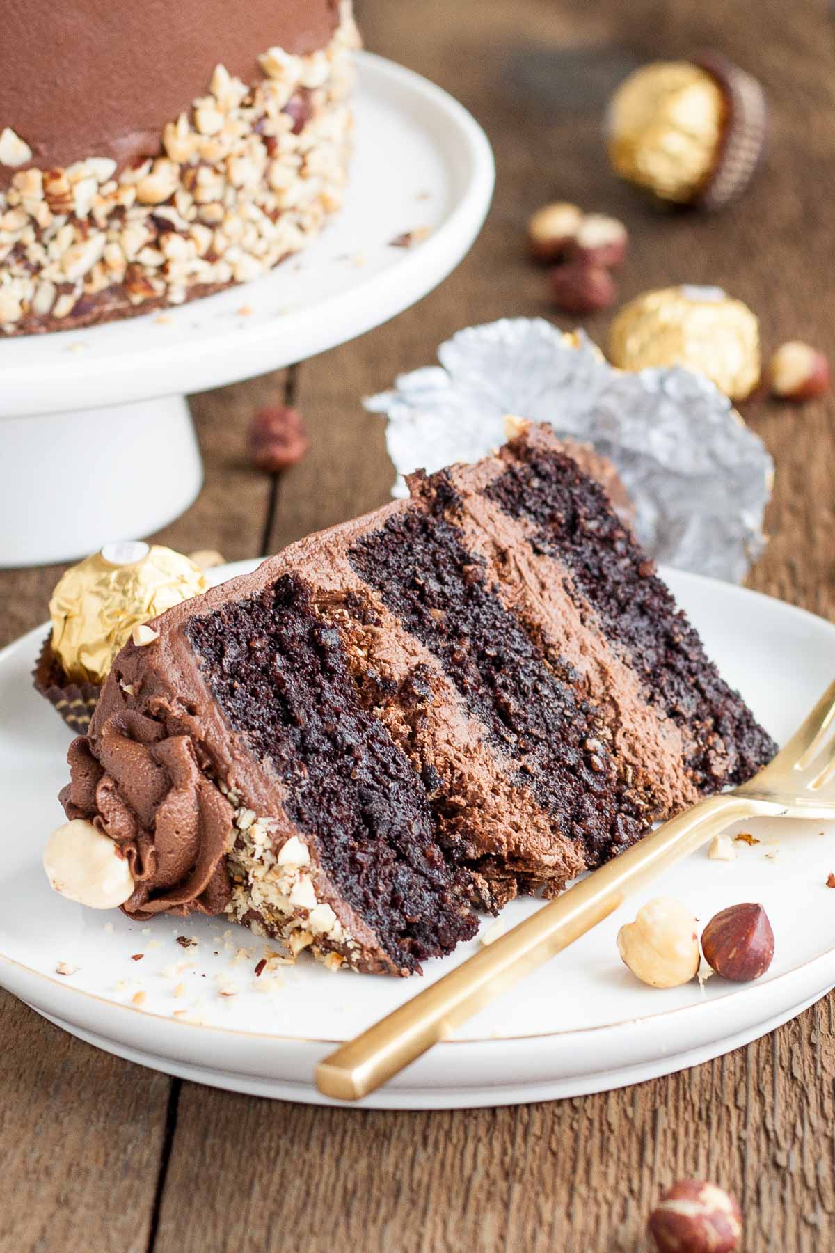 Slice of Ferrero Rocher Cake on a plate with a gold fork.