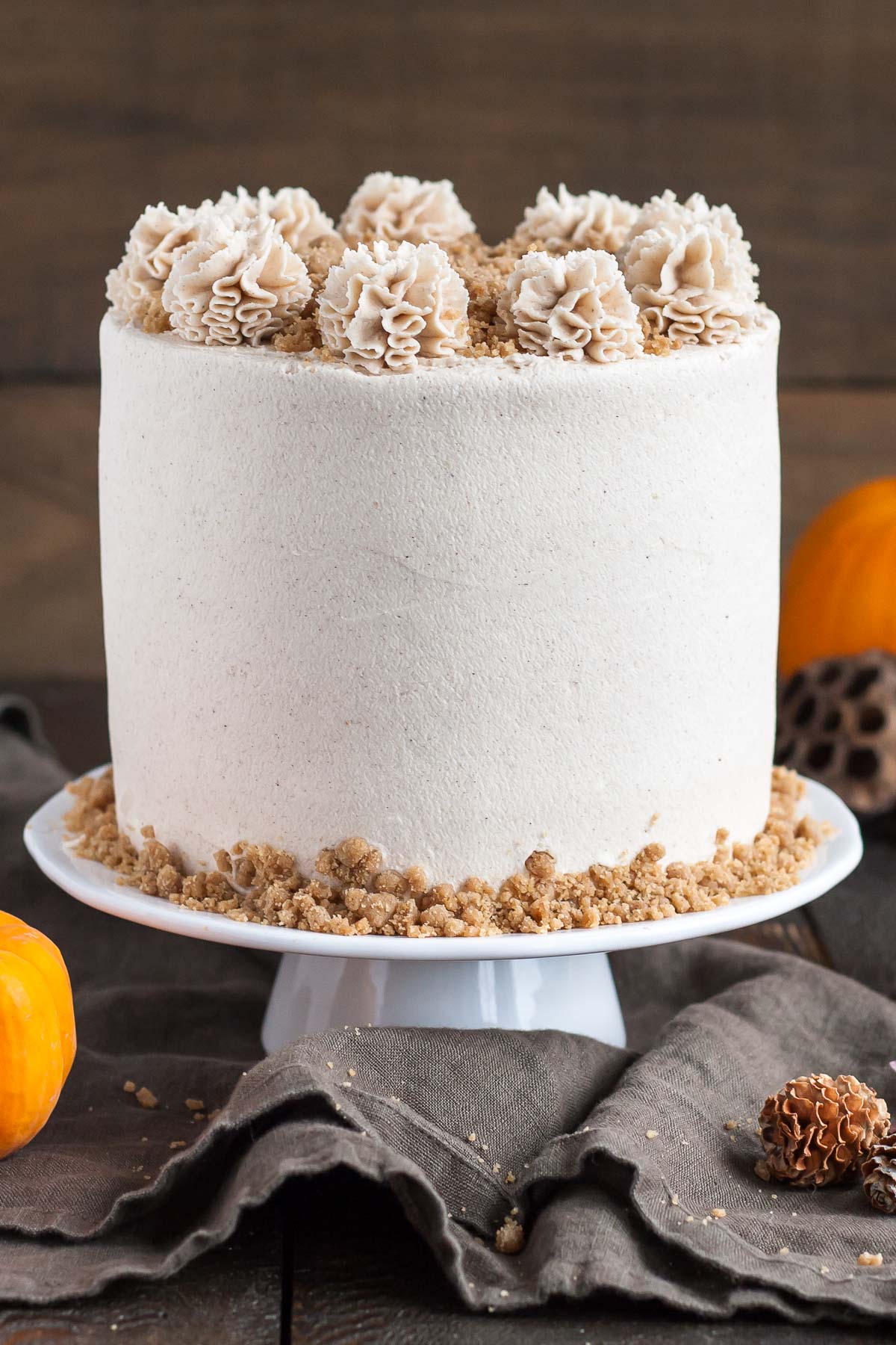 Cake on a cake stand with fall decor in the background.