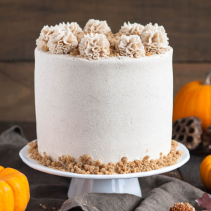 Cake on a cake stand with fall decor in the background.