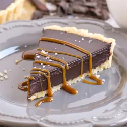 Slice of chocolate ganache tart on a plate with caramel drizzle.