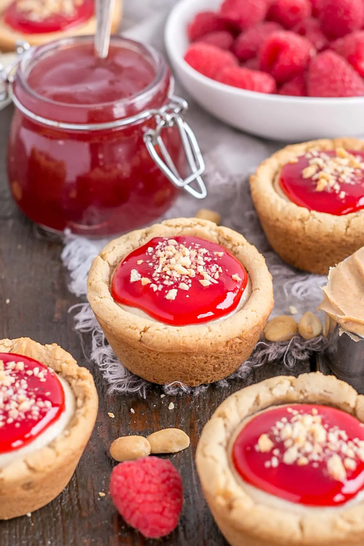 Cookie cups on a wooden table with jam in the background.