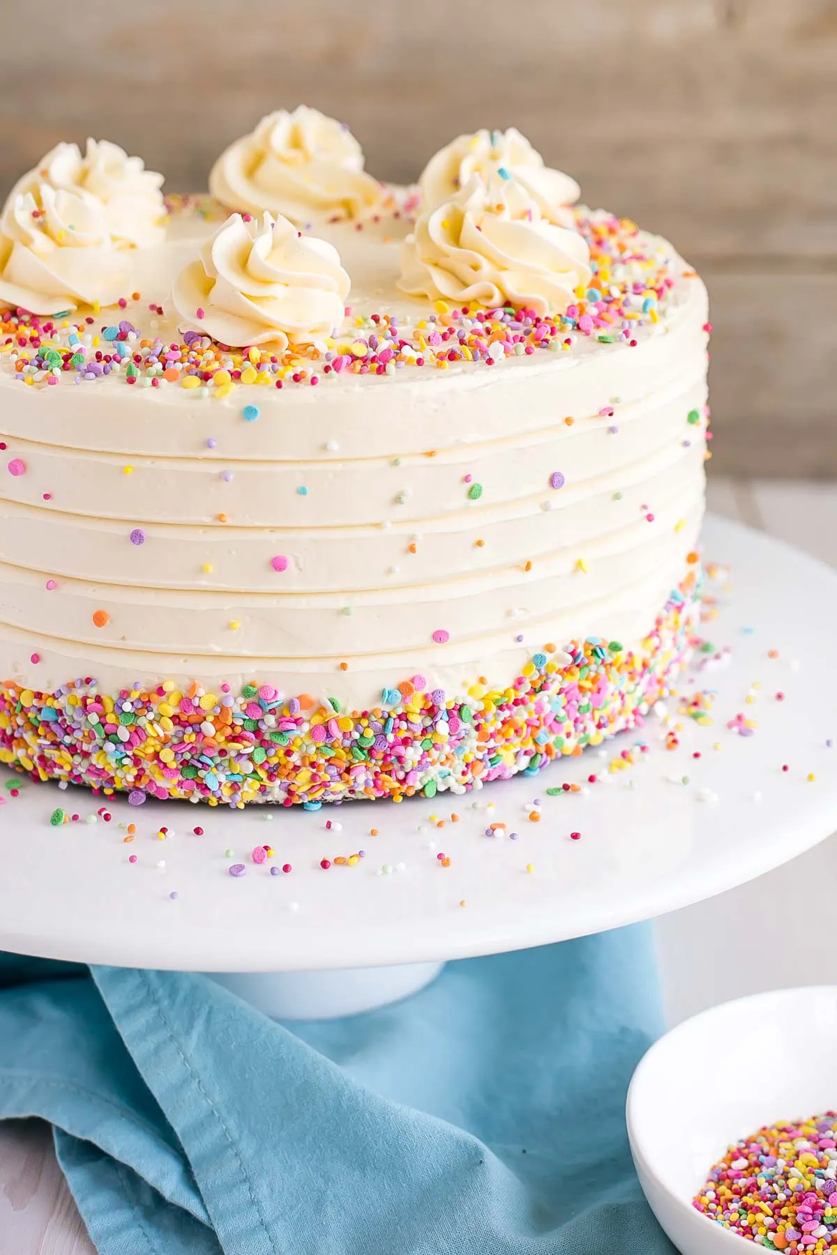 Bolo de baunilha com creme de manteiga de baunilha, confete em borras e rosetas.