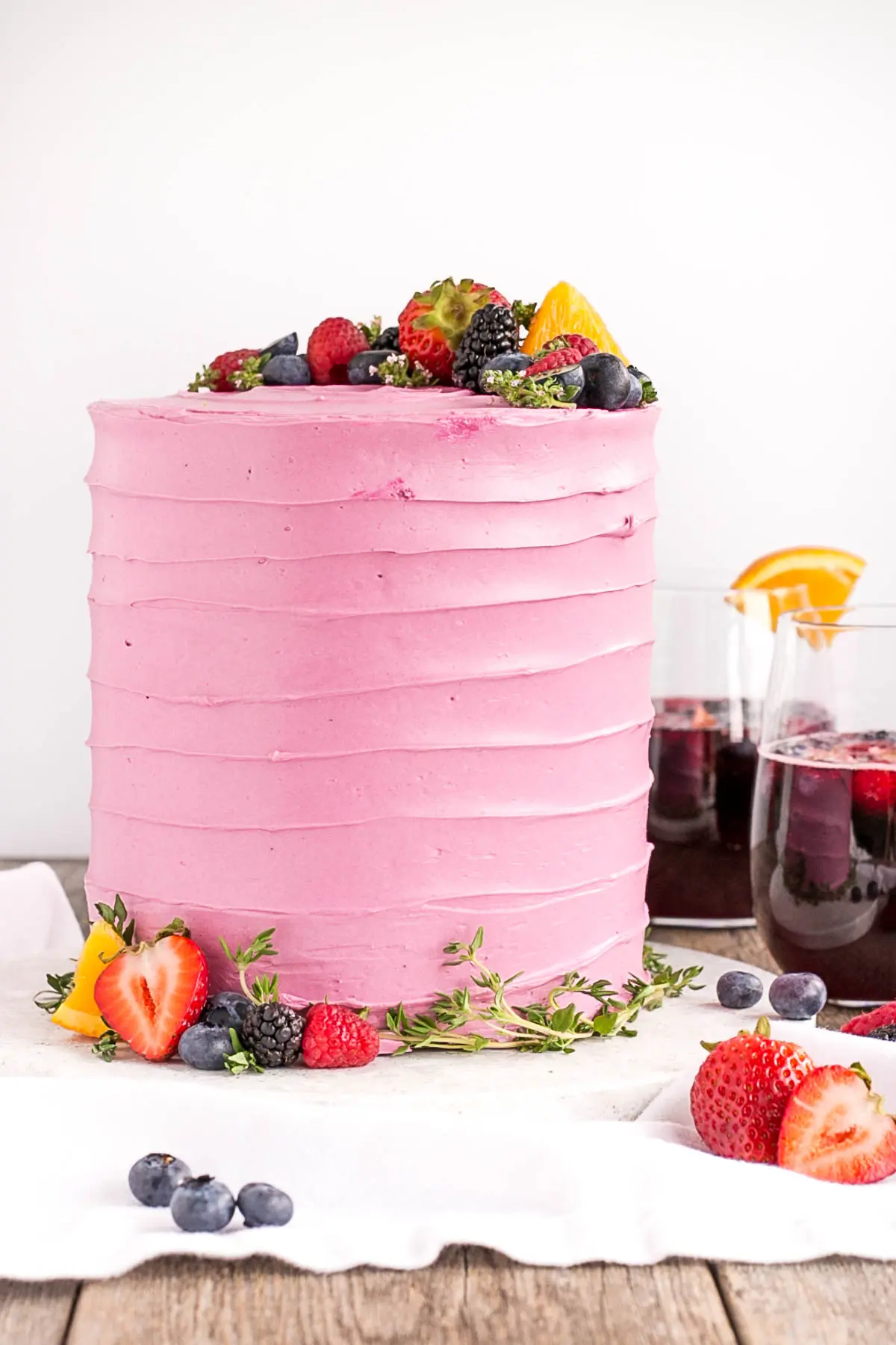 Cake on a white cake plate with sangria in glasses in the background.