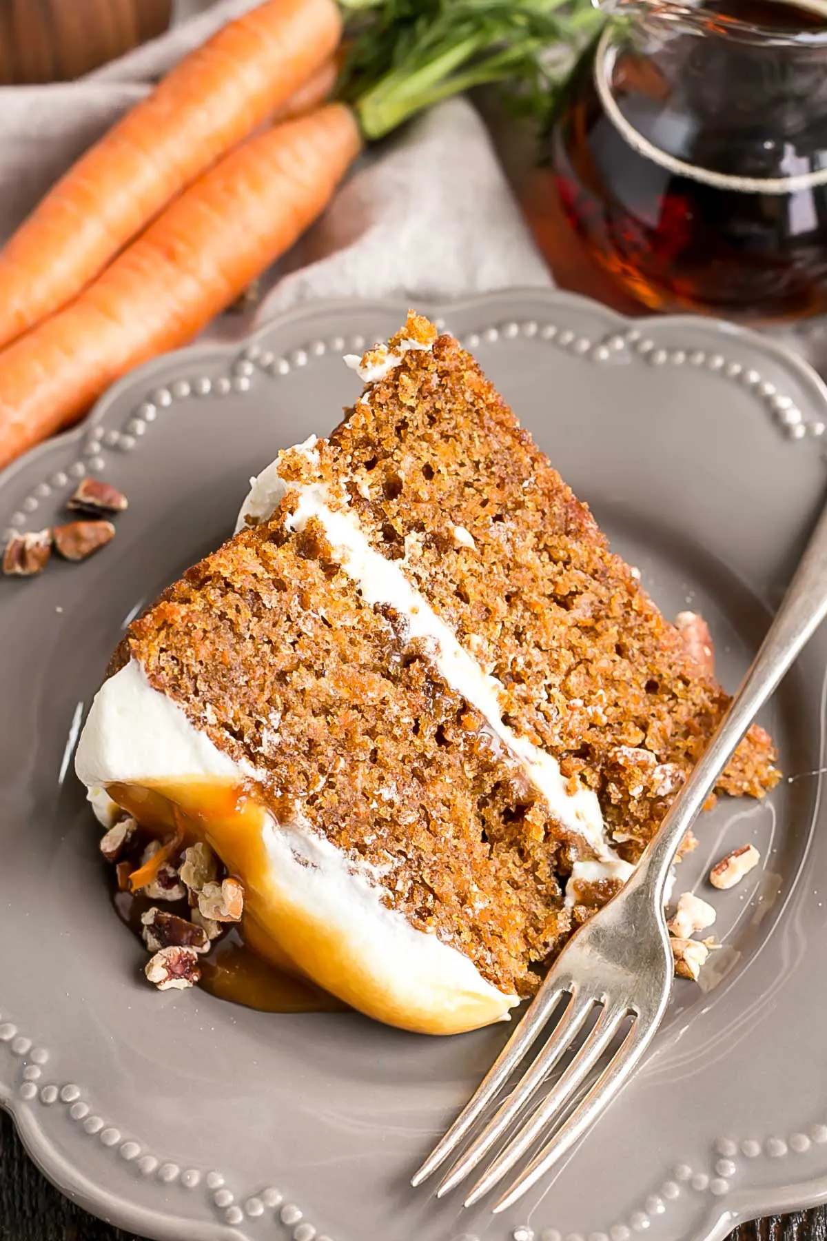 A piece of maple caramel carrot cake on a plate with a fork