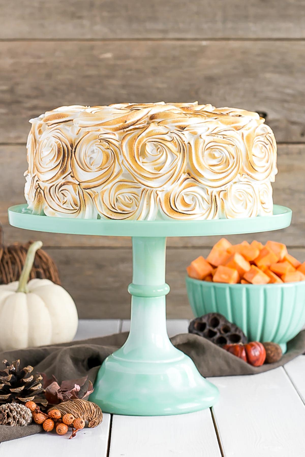 Cake on a mint green cake stand with fall decor in the background.