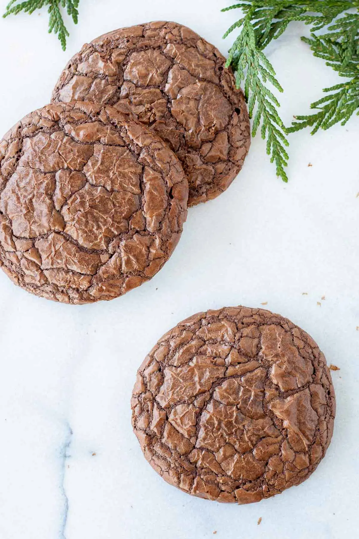 Picture of three brownie cookies on a marble surface.