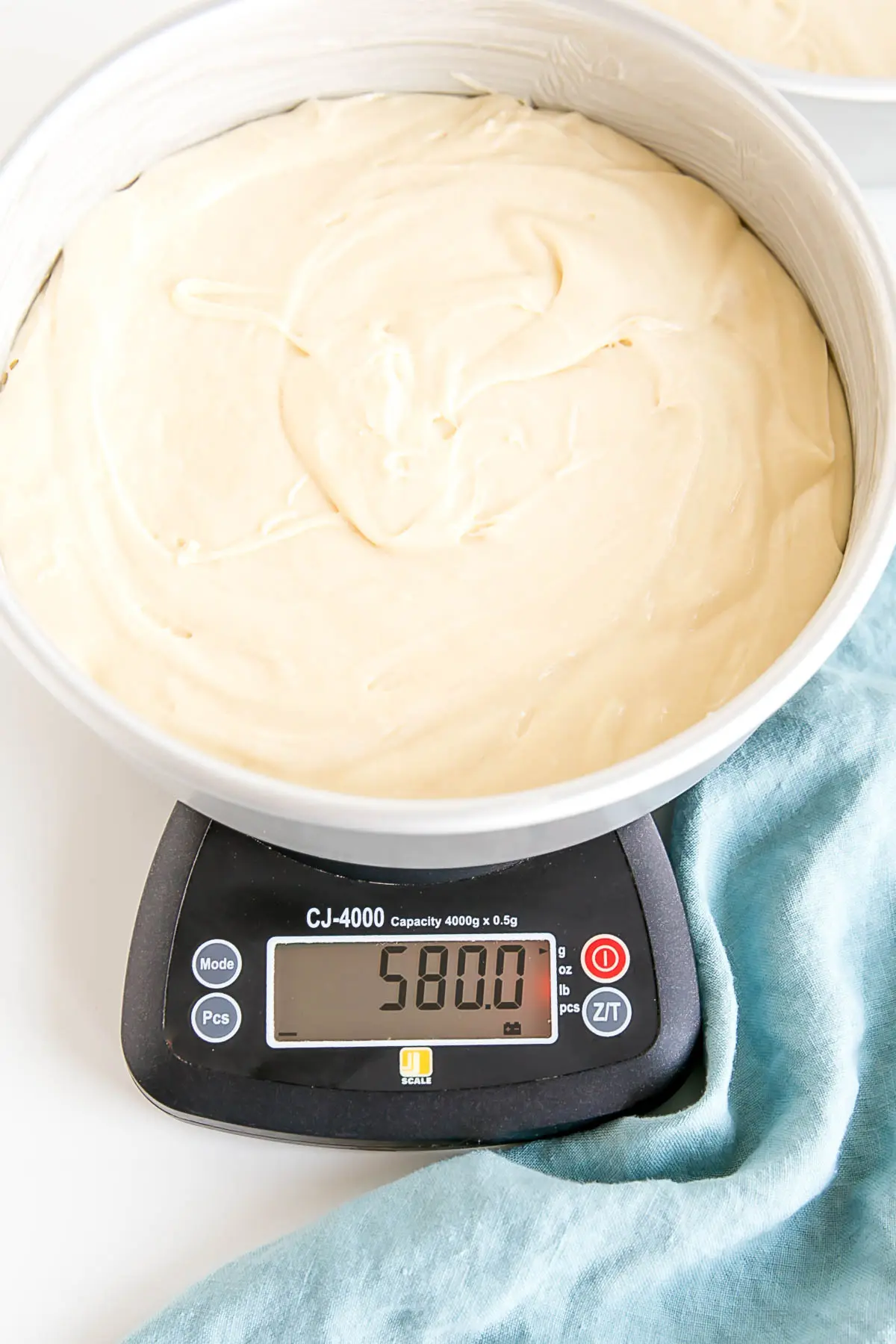 Cake pan filled with cake batter on a kitchen scale.