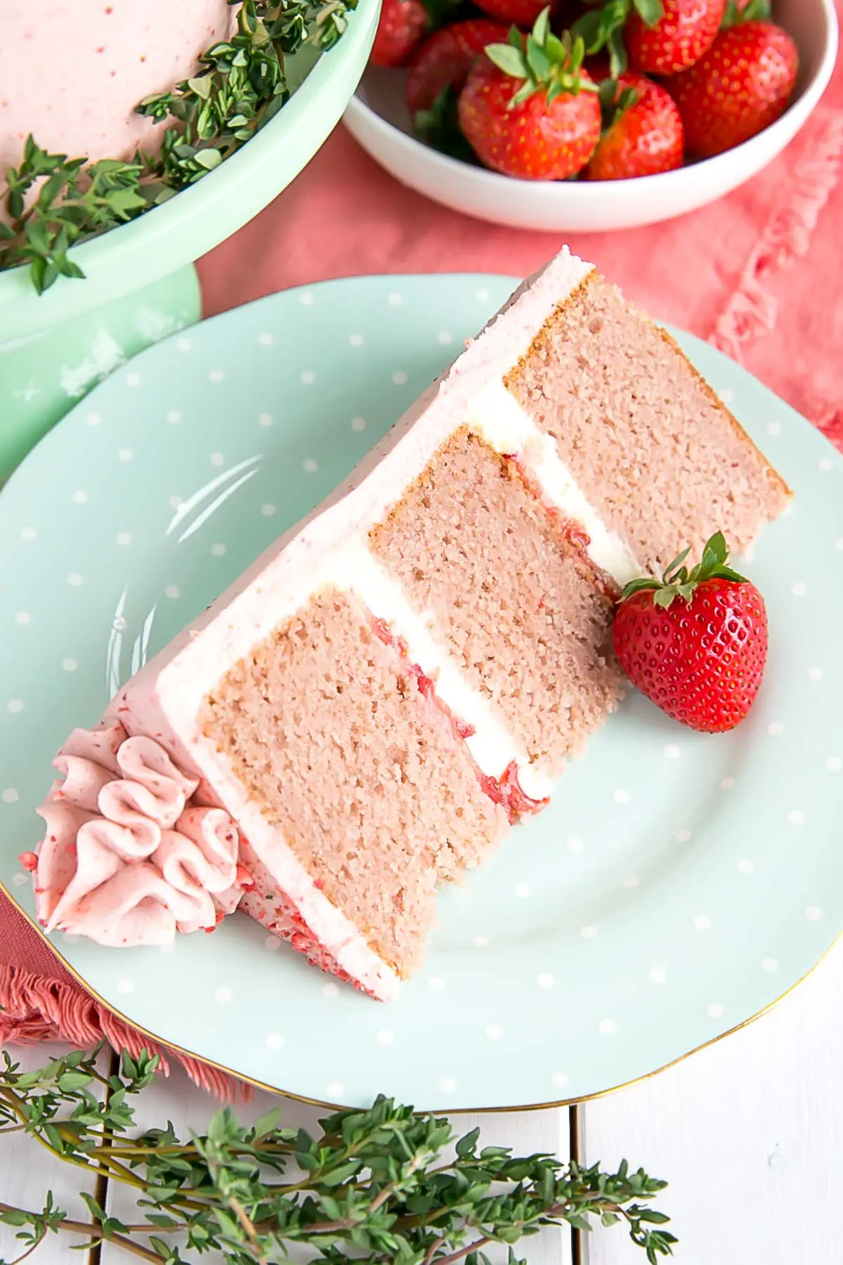 A slice of strawberry cake with fresh strawberries and mascarpone buttercream.