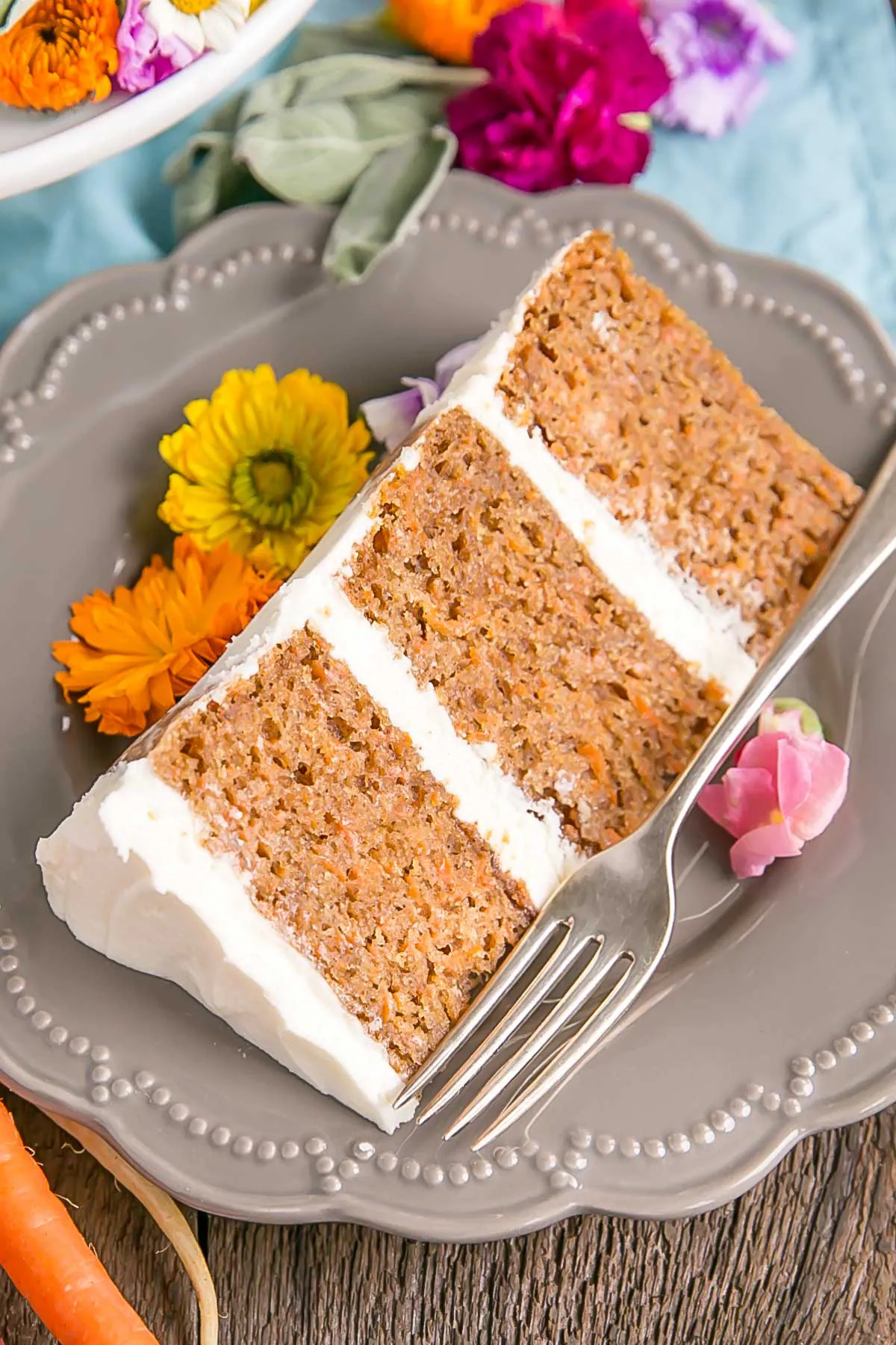 Cut slice of a carrot cake with cream cheese frosting.