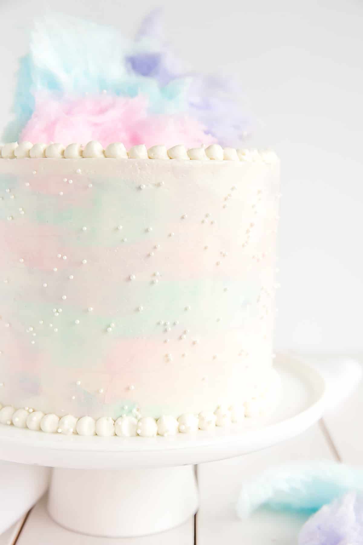 Close up of cotton candy cake decorated with a pearl border.