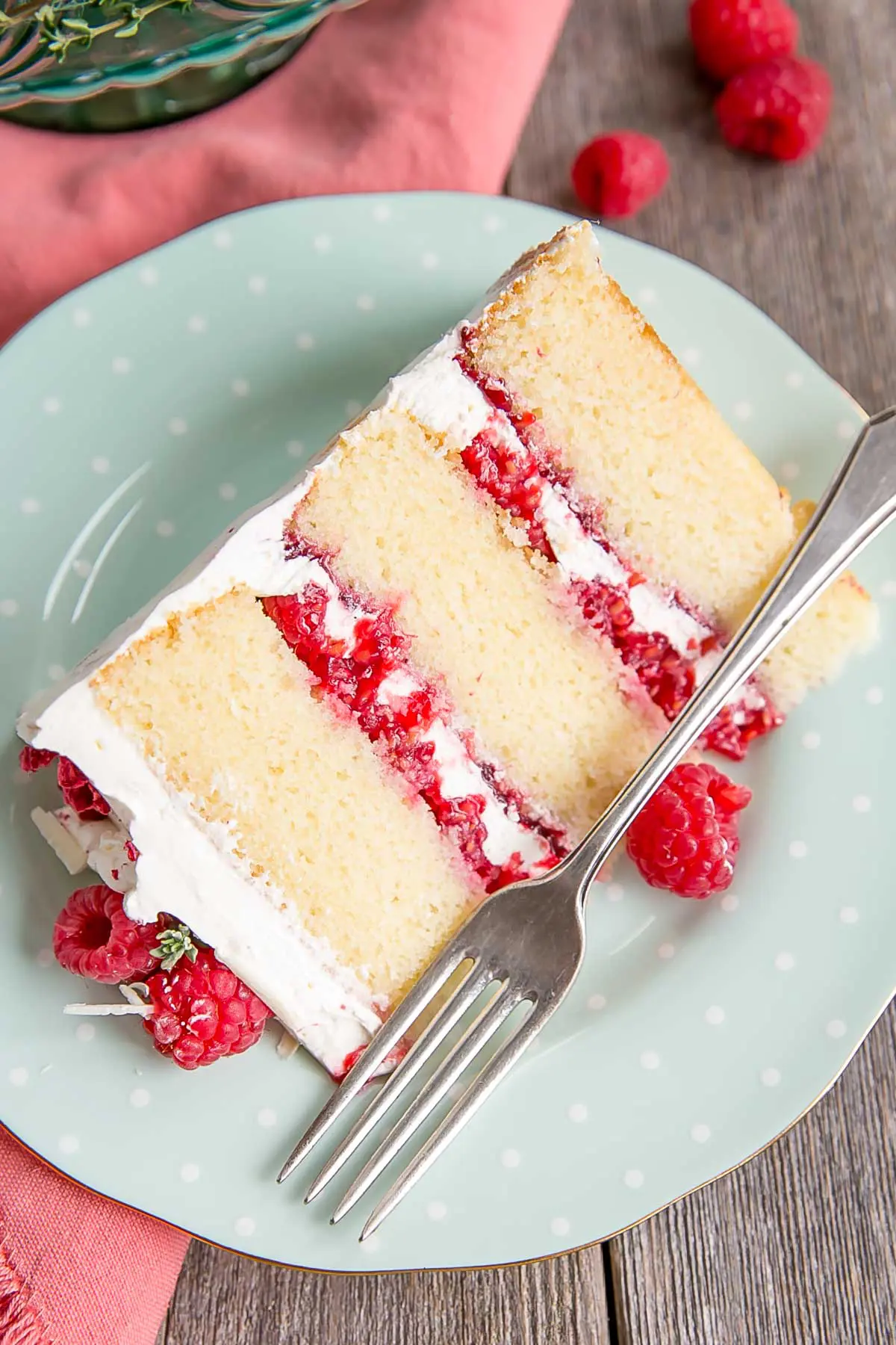 Slice of white chocolate cake with fresh raspberries.