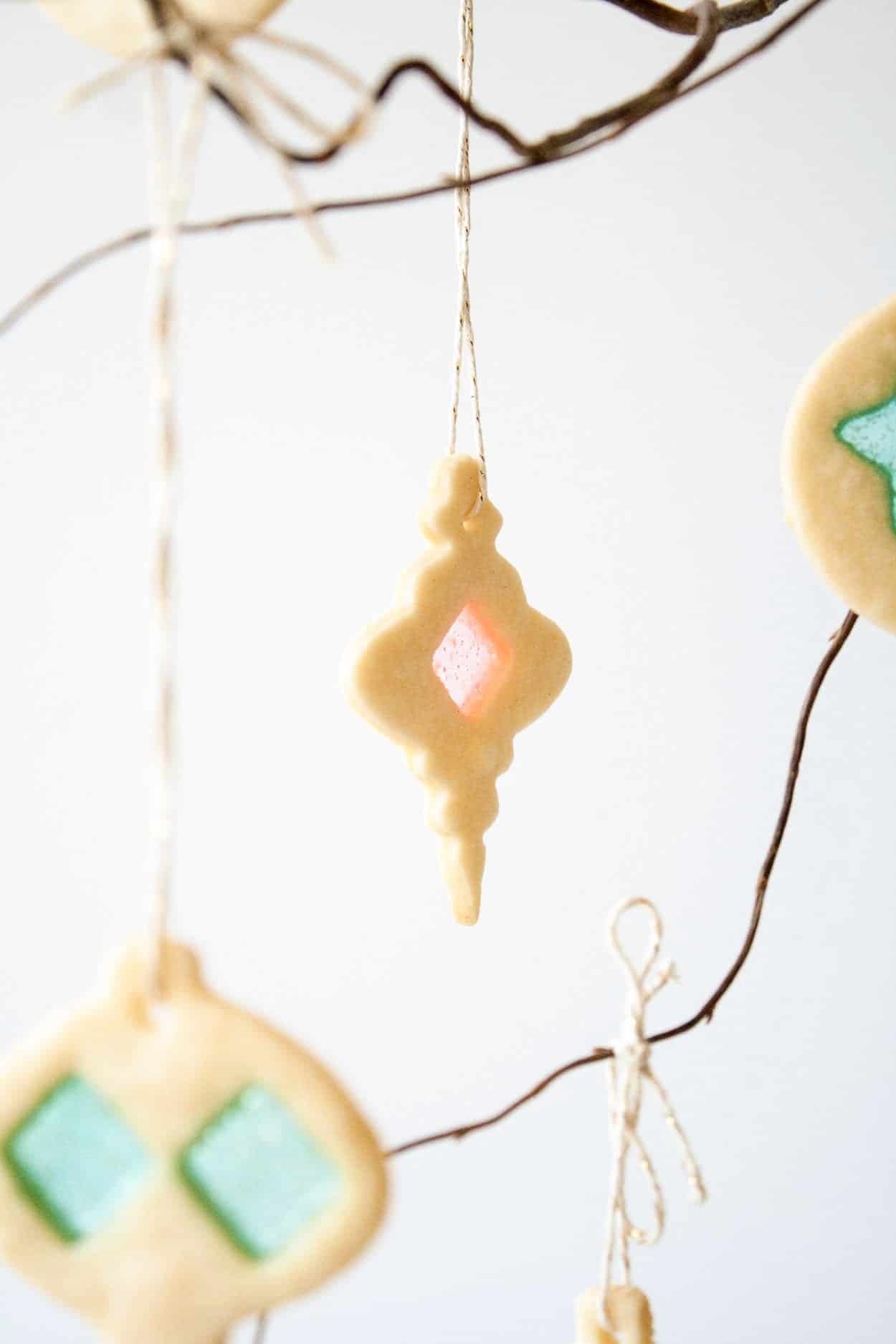 Close up of a stained glass cookie hanging from a branch.