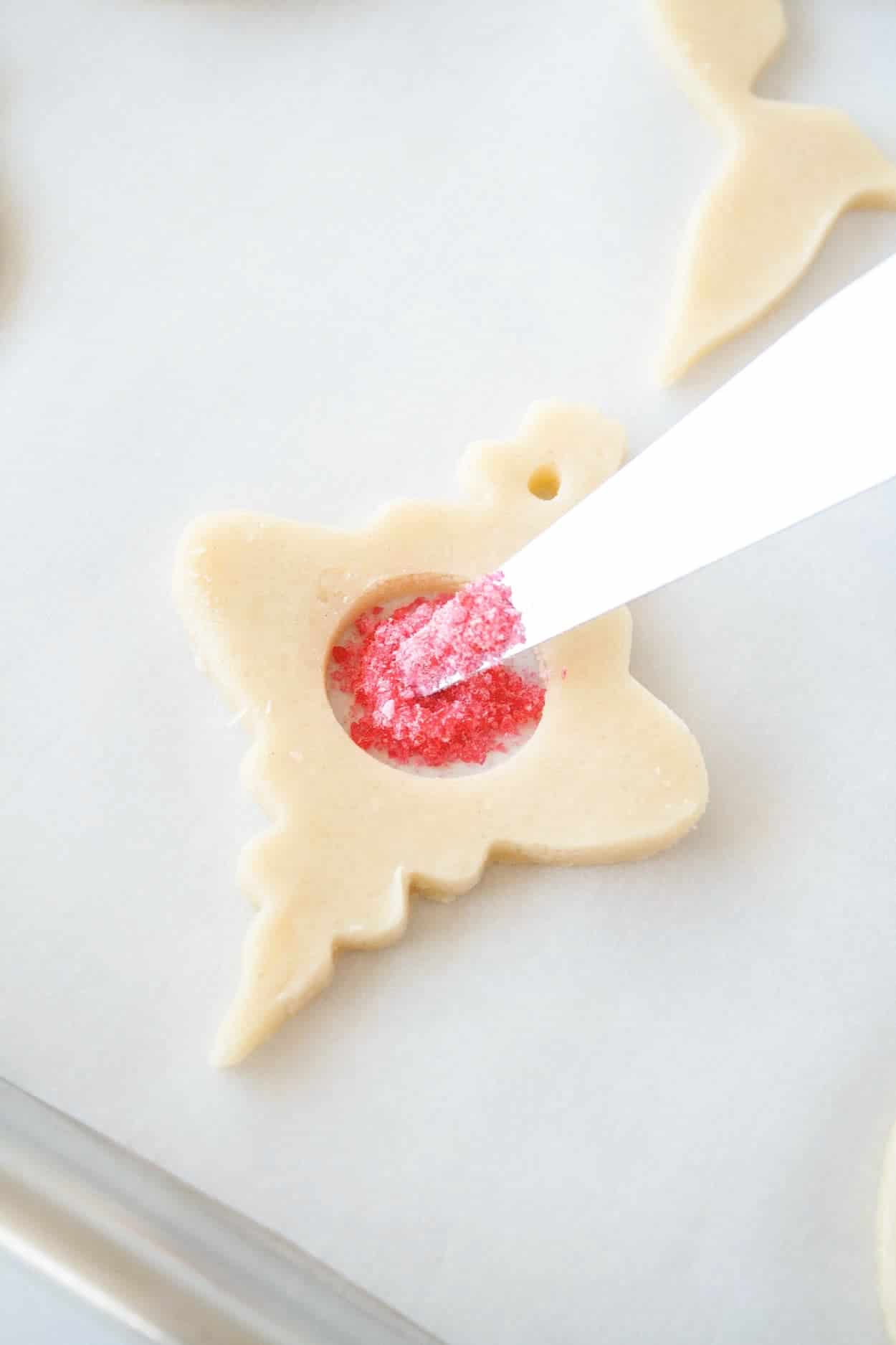 Cut out cookie being filled with sanding sugar