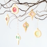 Stained glass cookies hanging from a tree branch.