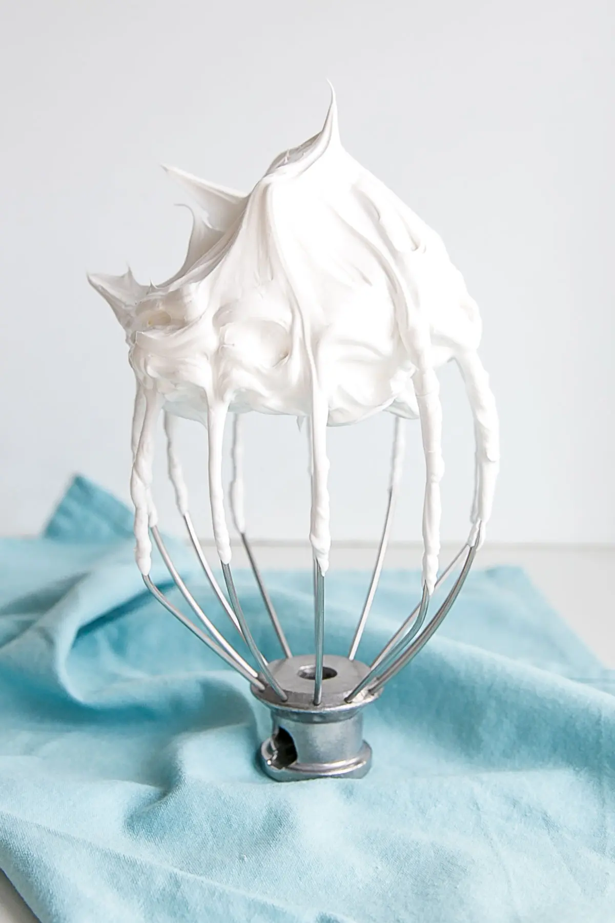Picture of a stiff peak meringue on a stand mixer whisk.