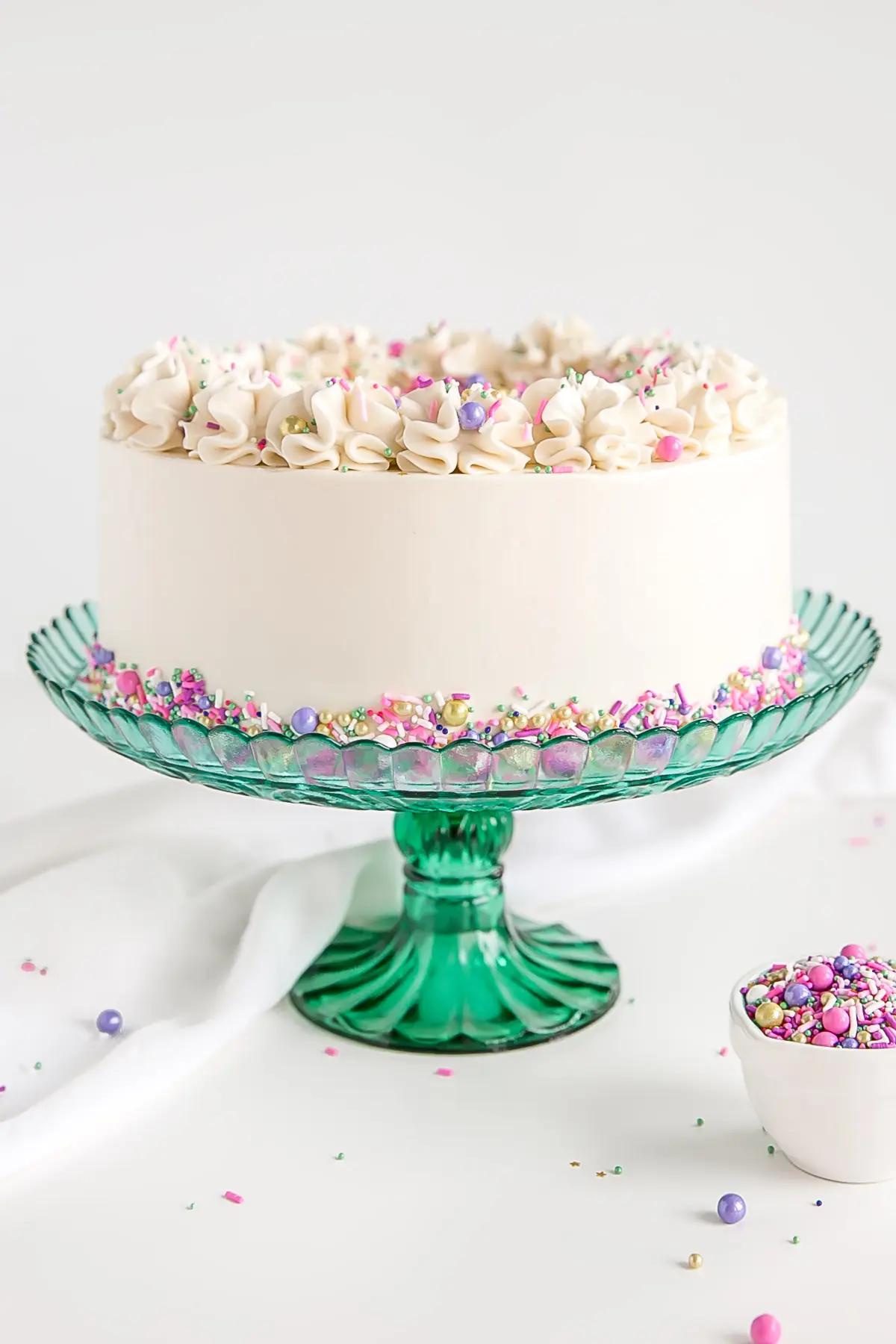 White cake recipe with white Swiss meringue buttercream and sprinkles.