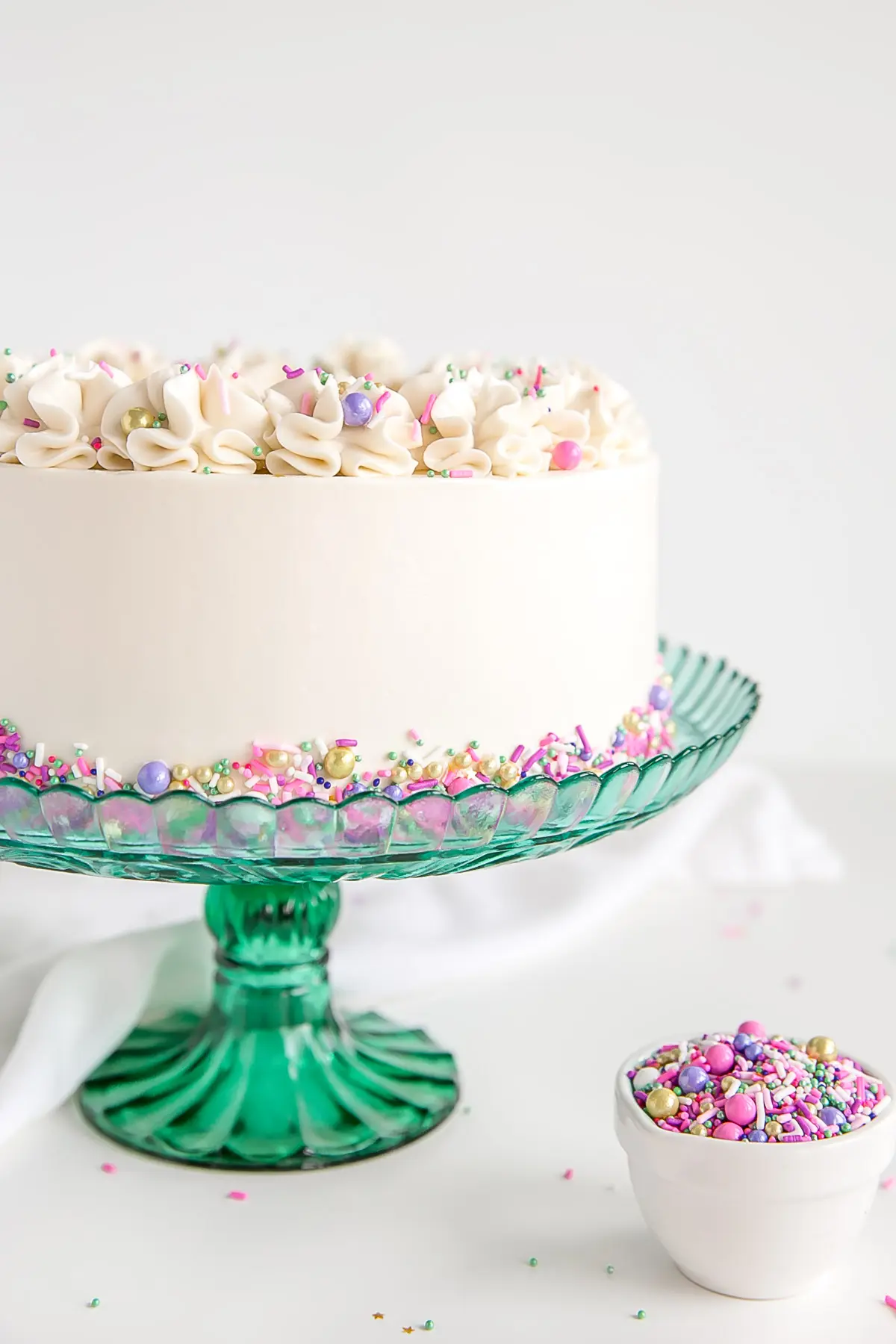 Side shot of a white cake on a green cake stand.