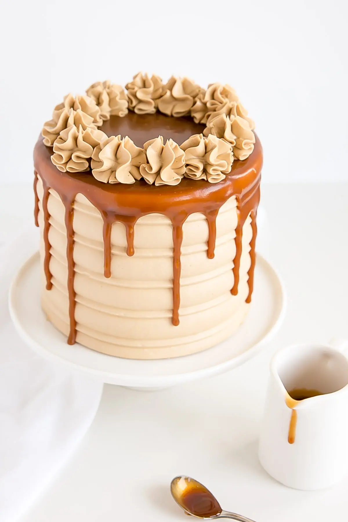 Caramel Cake with a caramel drip and rosettes on top.