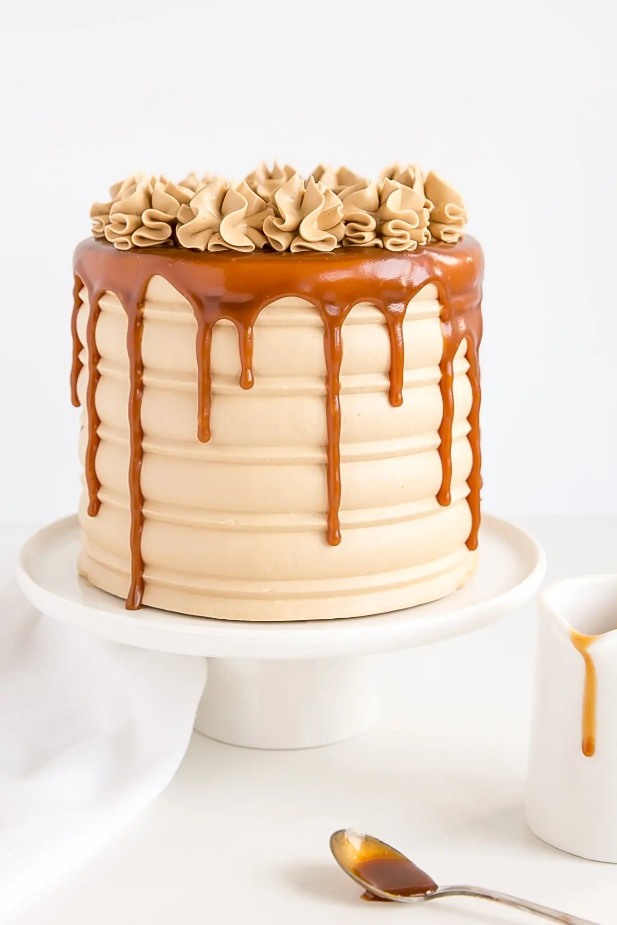 Caramel Cake with a small pitcher of caramel on the side. Caramel drip and rosettes.